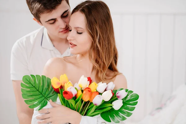 Un homme a donné à sa bien-aimée femme un bouquet de tulipes colorées. étreinte tendre. — Photo
