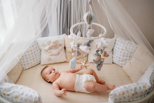 View from above. a baby lies in a white crib with mobile with toys. — Φωτογραφία Αρχείου