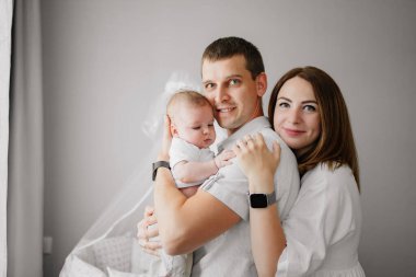 Yeni doğmuş bir bebeği olan mutlu bir aile karyolanın yanında. Anne, baba ve bebek.