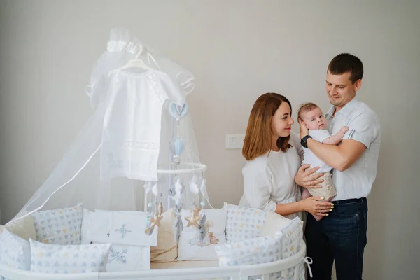 a happy family with a newborn baby at home near the cot. mom, dad and baby.