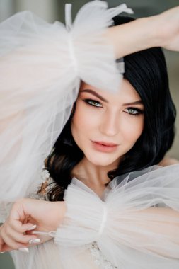 Yakın plan. Beyaz elbiseli, şeffaf kollu güzel esmer gelin.