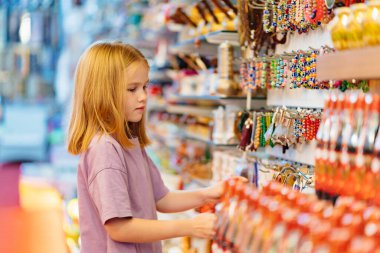 Komik küçük bir kız dükkandaki mücevher ve hediyeliklerle ilgileniyor.. 