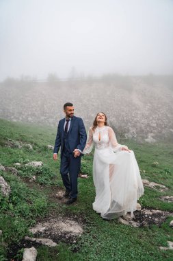 Yeni evliler puslu bir havada el ele yürür. Yolculukta düğün