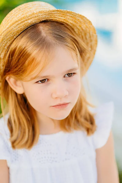 Portrait of a cute little girl with blonde hair in a straw hat. — Photo