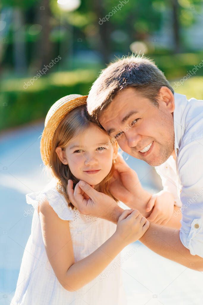  Dad gently and lovingly holds his daughters face with his hands. 