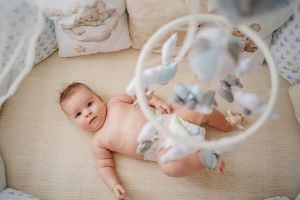 View from above. a baby lies in a white crib with mobile with toys. — Φωτογραφία Αρχείου