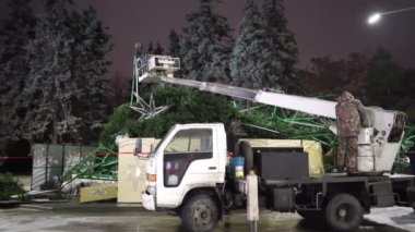 İşçiler şehir caddesinde büyük bir yapay Noel ağacını söküyorlar..