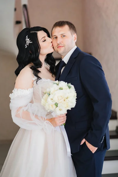 Gli sposi in abiti da sposa con un mazzo di fiori stanno insieme — Foto Stock