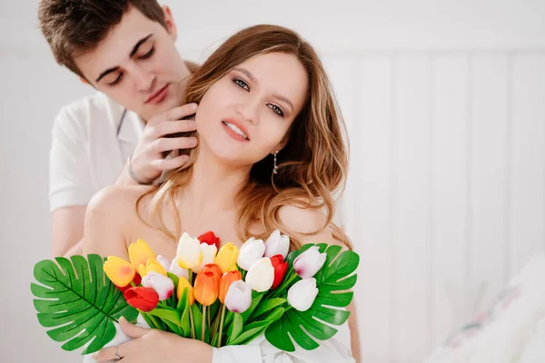 Ein Mann schenkte seiner geliebten Frau einen Strauß bunter Tulpen. Zärtliche Umarmung. — Stockfoto