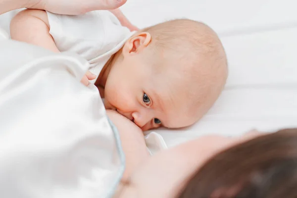Amning. på nära håll. modern matar barnet med bröstmjölk liggande i sängen — Stockfoto
