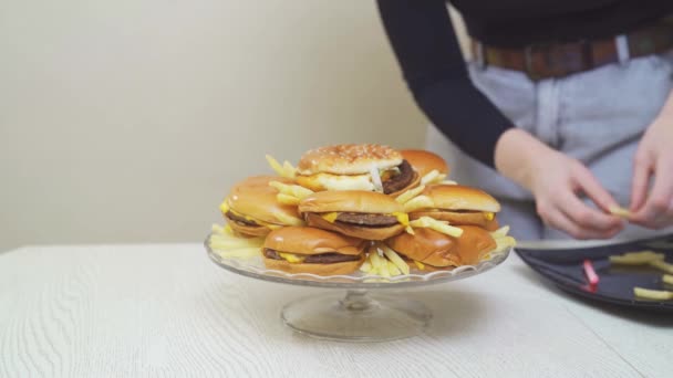 Kobieta umieszcza cheeseburgery i frytki na okrągłym szklanym naczyniu. oryginalny tort — Wideo stockowe