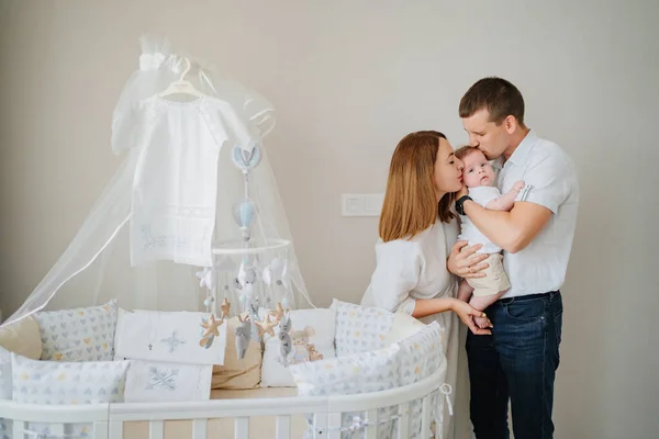 a happy family with a newborn baby at home near the cot. mom, dad and baby.