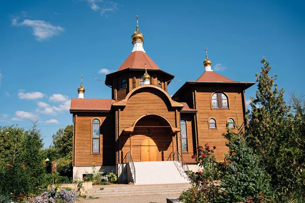 The building of a wooden Orthodox church surrounded by a garden in clear weather — Stock Photo, Image