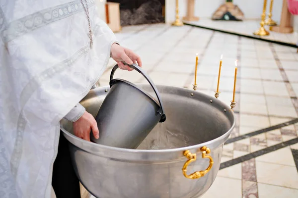Prästen häller vatten i dopfunten. — Stockfoto
