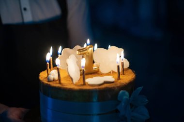 Kurdelelerle süslenmiş bir pasta ve karanlıkta yanan mumlarla dolu şeker bulutları.