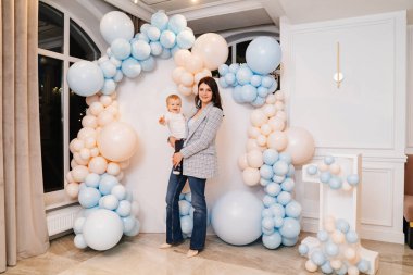 Mutlu anne ve oğul balonlarla fotoğraf alanının önünde.