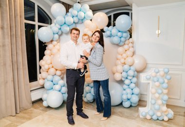 Mutlu baba, anne ve oğul balonlarla fotoğraf alanının önünde.