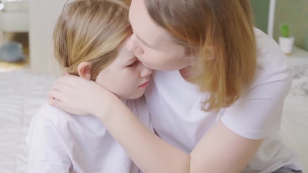 Mamá abraza y consuela a su pequeña hija molesta en casa. — Vídeo de stock