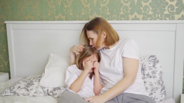 Mutter umarmt und tröstet ihre aufgebrachte kleine Tochter im Schlafzimmer — Stockvideo