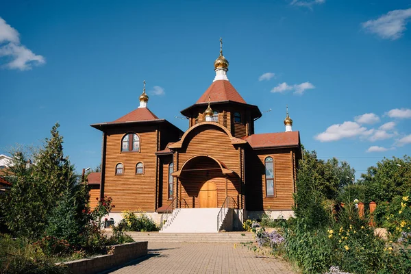 Der Bau einer orthodoxen Holzkirche, die bei klarem Wetter von einem Garten umgeben ist — Stockfoto