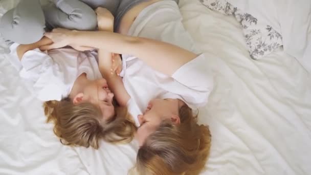 Överst. Mamma och dotter skrattar med kittling på sängen. spel av barn — Stockvideo