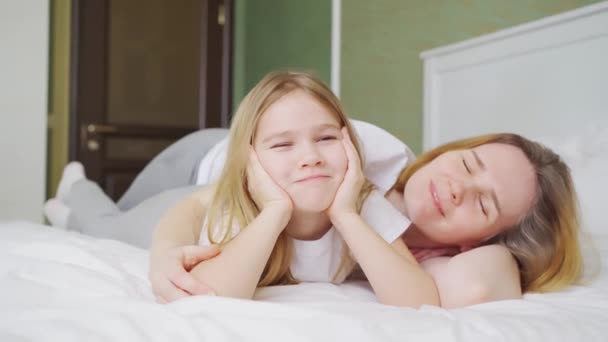 Μαμά και κόρη στο κρεβάτι διασκεδάζουν, φιλιούνται και αγκαλιάζονται. — Αρχείο Βίντεο