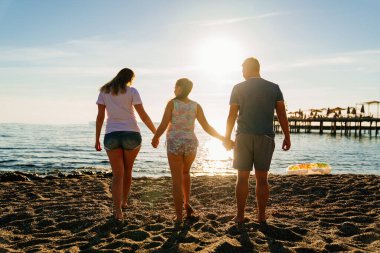 Dikiz aynası. Deniz kıyısında güneş ışığı altında bir aile. Tatil köyünde aile tatilleri.