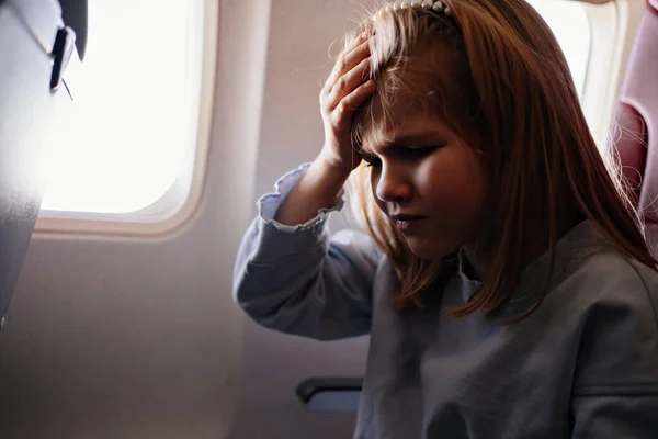 어린 소녀가 비행기 멀미때문에 머리를 잡고 있는 모습 — 스톡 사진