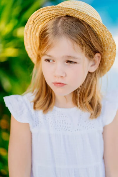Triste portrait d'une petite fille aux cheveux blonds dans un chapeau de paille. caprices d'enfants — Photo