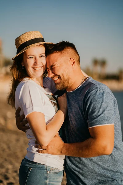 Un uomo e una donna innamorati che ridono abbracciati sulla spiaggia. sposi novelli nel resort. — Foto Stock