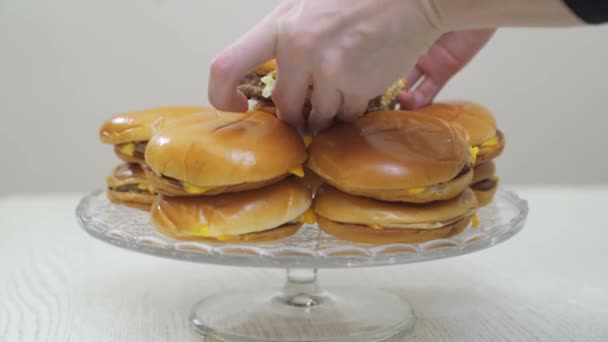 Ruce položte cheeseburgery na kulatý skleněný talíř. fast food. originální dort. — Stock video