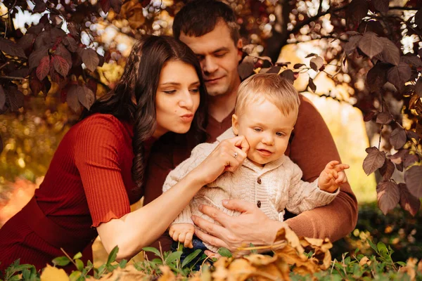 Uma família feliz com uma criança pequena em um passeio de outono no parque. — Fotografia de Stock