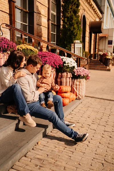 Sonbahar çiçekleriyle süslenmiş merdivenlerde küçük bir çocukla mutlu bir aile.. 