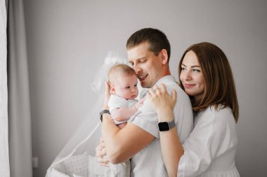 Yeni doğmuş bir bebeği olan mutlu bir aile karyolanın yanında. Anne, baba ve bebek.