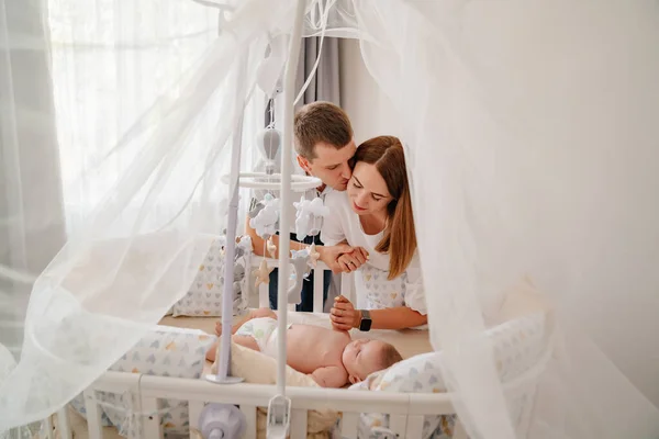 Parents près d'un bébé se trouve dans une crèche blanche avec auvent — Photo