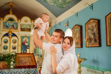 Kilisenin penceresinde açık renkli cüppeli bir erkek ve bir kadın ve bir çocuk.. 