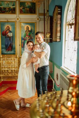 Kilisenin penceresinde açık renkli cüppeli bir erkek ve bir kadın ve bir çocuk.. 