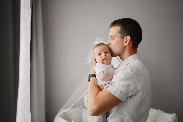 Um pai segura seu filho recém-nascido em seus braços e o beija. — Fotografia de Stock
