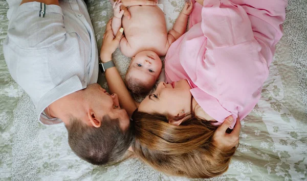 Los padres se acuestan con el bebé. la felicidad de la maternidad. — Foto de Stock