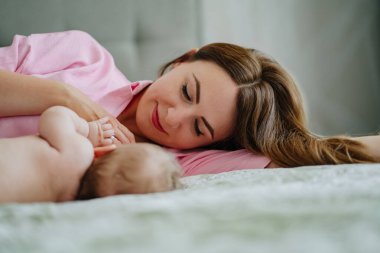 Annem bebekle yatakta yatıyor. Anneliğin mutluluğu. Emzirme.