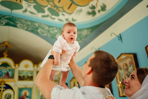 Hombre y mujer con bebé hijo en túnicas de color claro por ventana en la iglesia. — Foto de Stock