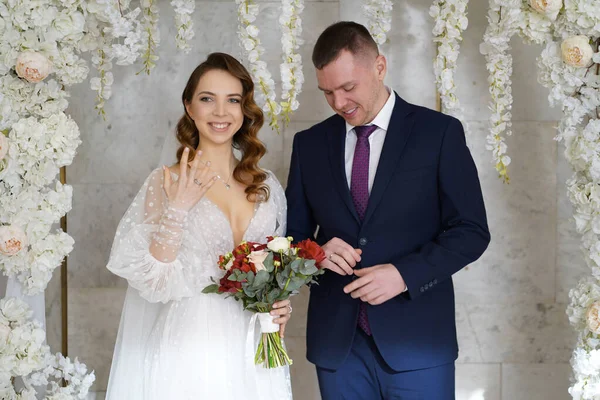 Troca de casamento rings.bride e noivo em um arco de flores na cerimônia de casamento — Fotografia de Stock