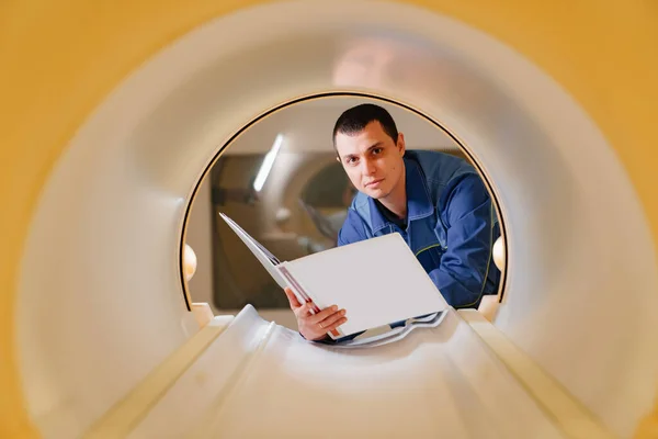Инженер-установщик аппарата МРТ в сканере с инструкциями в руке — стоковое фото