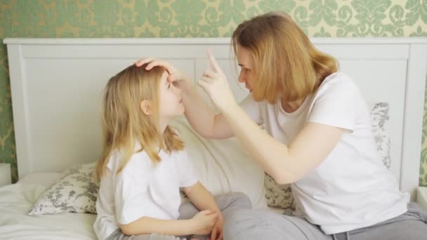 Figlia si lamenta di una pagliuzza o dolore agli occhi e la madre la esamina. — Video Stock