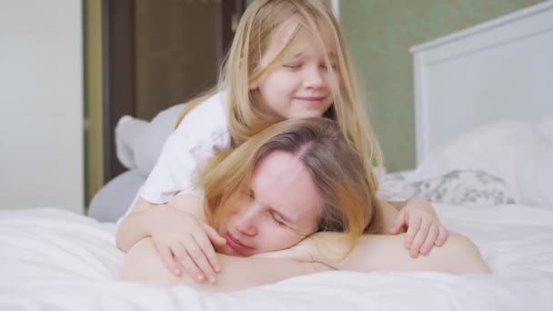 Mutter und Tochter sitzen im Bett, haben Spaß und umarmen sich. — Stockvideo