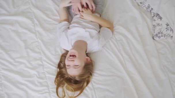 Ansicht oben. lacht ein kleines Mädchen mit einem Kribbeln auf dem Bett. Kinderspiele — Stockvideo