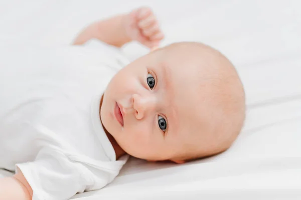 Lindo bebé con una camiseta blanca en una sábana blanca. pediatría — Foto de Stock