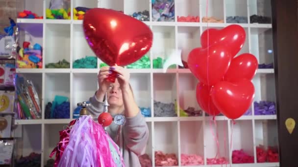 En kvinde puster af helium fra en folie ballon i form af et hjerte. – Stock-video