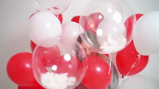 Een blonde vrouw danst en heeft plezier met ballonnen op een witte achtergrond. — Stockvideo