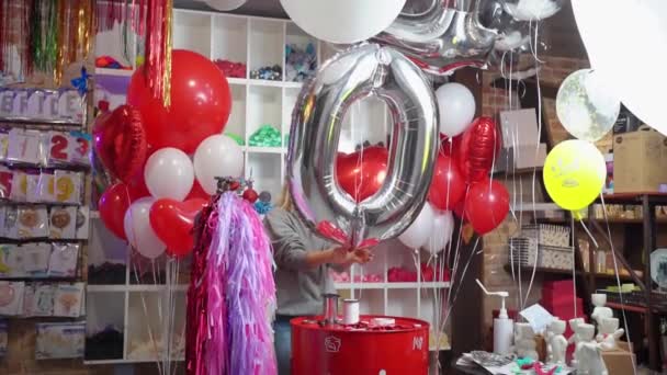 Una mujer infla un globo en forma de un gran número de plata para un cumpleaños — Vídeos de Stock